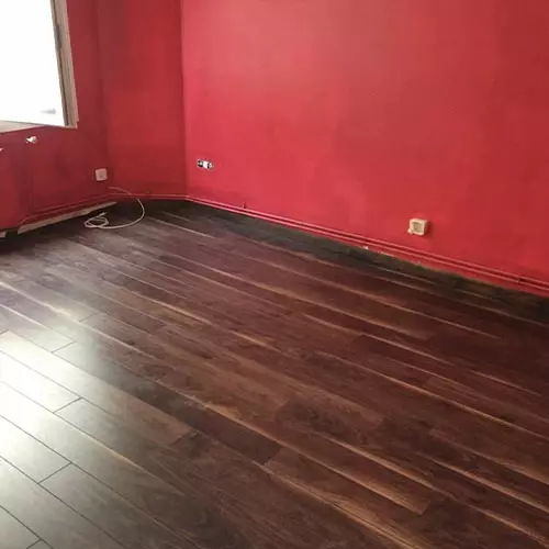 Parquet flottant foncé posé dans une pièce aux murs rouges